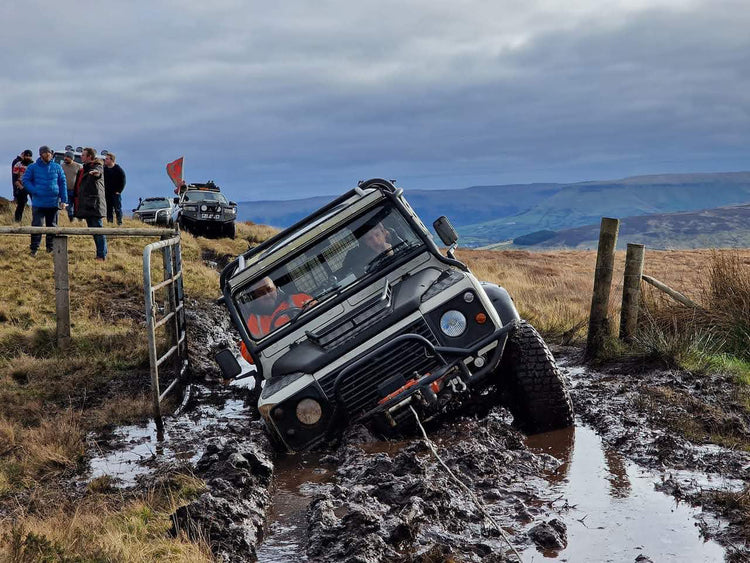 Land Rover Defender being pulled through deep mud.